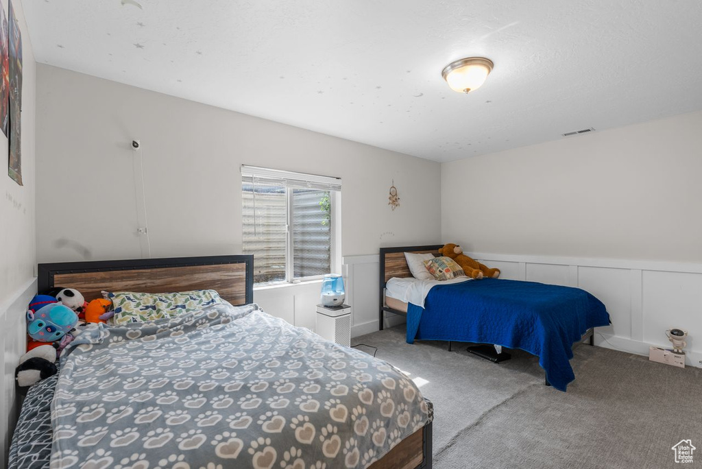 Carpeted bedroom featuring wainscoting