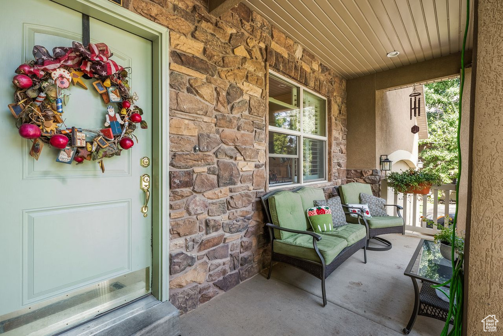 Doorway to property with stone siding and covered porch