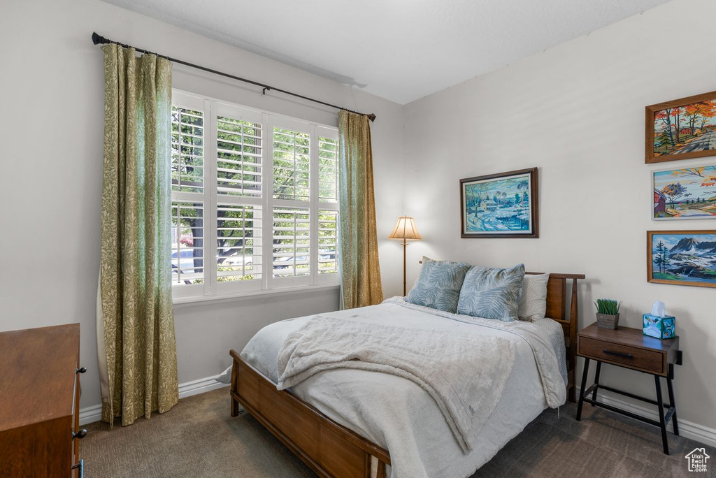 Bedroom with dark colored carpet and multiple windows