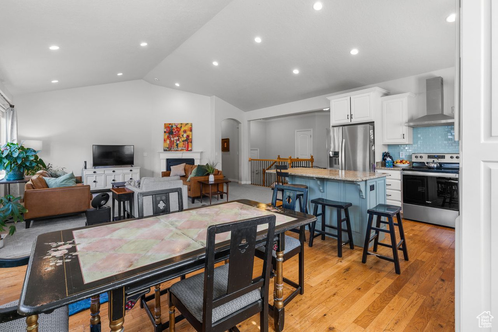 Dining room featuring light wood-style floors, recessed lighting, arched walkways, and high vaulted ceiling