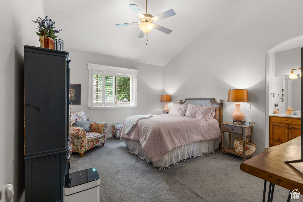 Carpeted bedroom featuring high vaulted ceiling, ensuite bath, a ceiling fan, and arched walkways