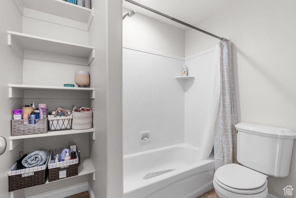 Bathroom with toilet and shower / bathtub combination with curtain