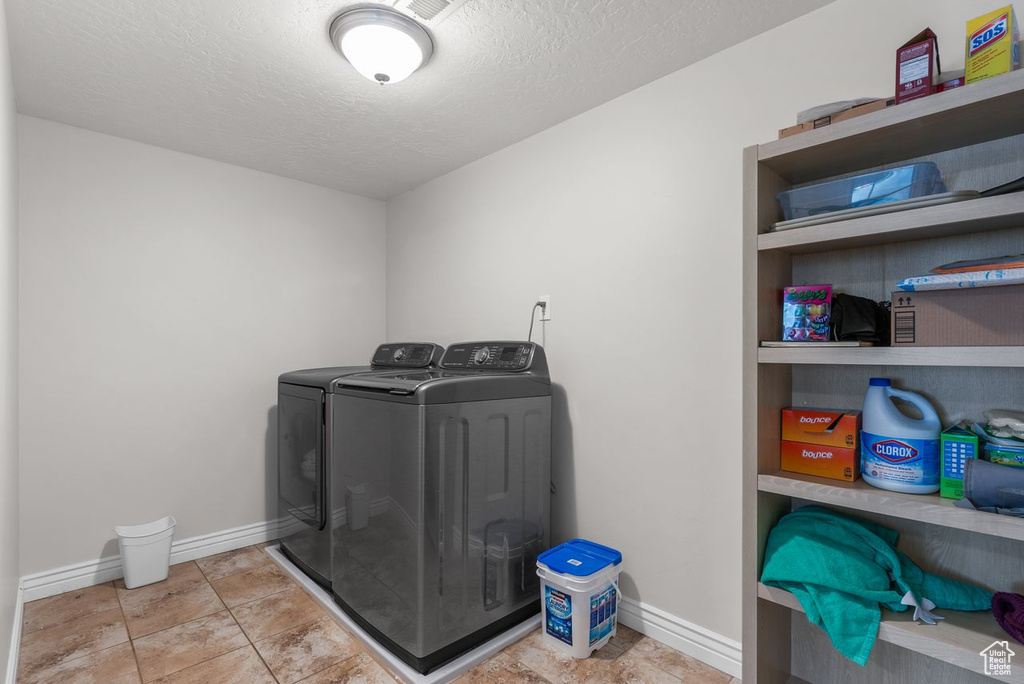 Washroom with washer and clothes dryer and a textured ceiling