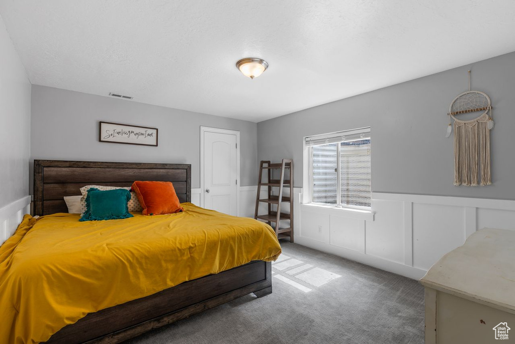 Carpeted bedroom featuring a wainscoted wall