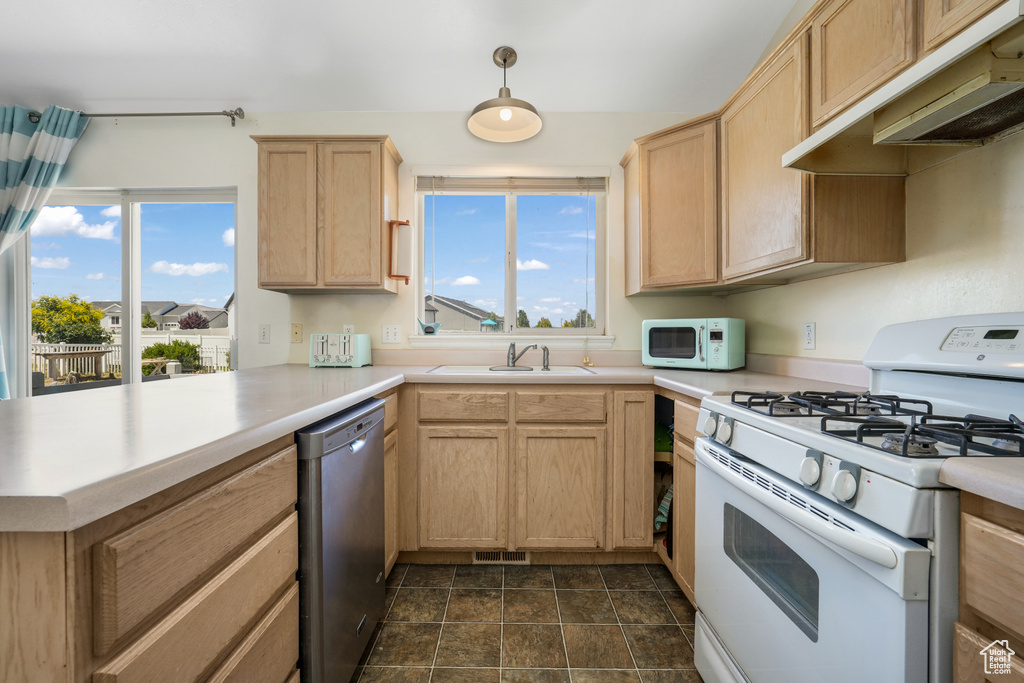 Kitchen with white appliances, light brown cabinets, a peninsula, and under cabinet range hood
