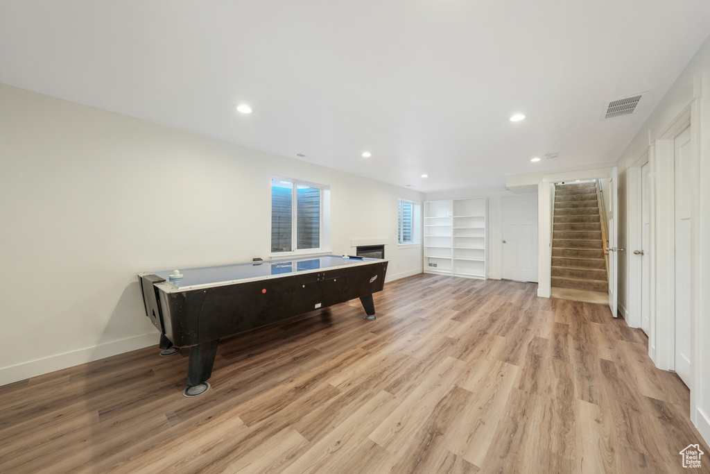 Playroom with light wood-style floors, a fireplace, recessed lighting, and built in shelves