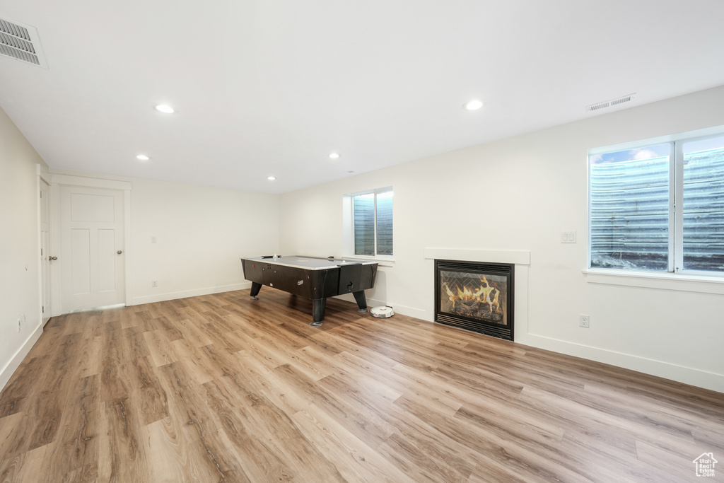 Playroom featuring light wood-style flooring, a glass covered fireplace, and recessed lighting