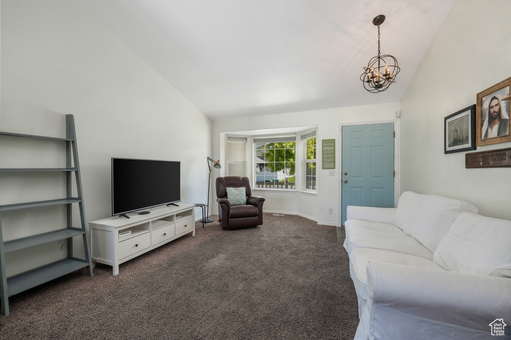 Living area with lofted ceiling, a chandelier, and dark colored carpet