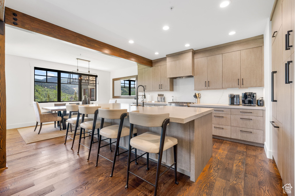 Kitchen with dark wood-type flooring, a breakfast bar area, light countertops, plenty of natural light, and recessed lighting