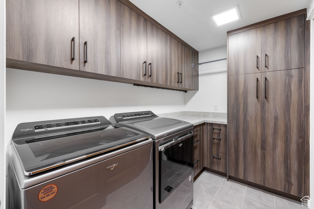 Laundry area with washer and dryer, cabinet space, and light tile patterned flooring