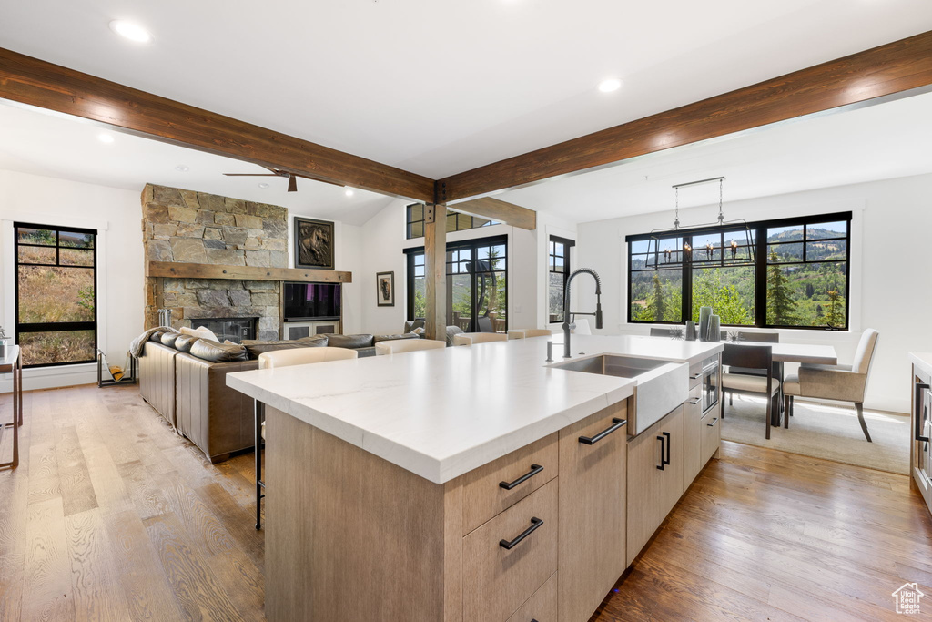 Kitchen with healthy amount of natural light, a kitchen island with sink, light wood-type flooring, beamed ceiling, and recessed lighting