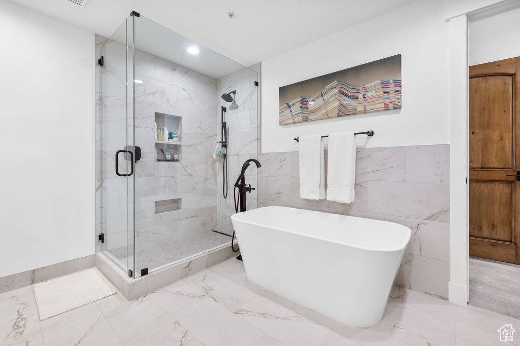 Full bath with a soaking tub, a stall shower, marble finish floors, recessed lighting, and tile walls