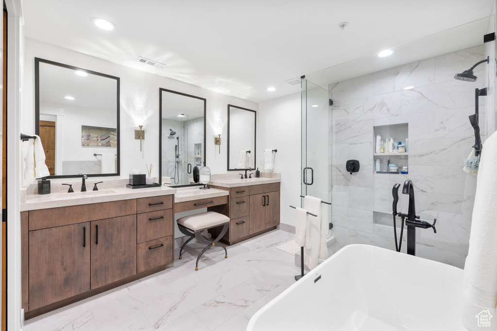 Full bath featuring marble finish flooring, a shower stall, a freestanding tub, vanity, and recessed lighting