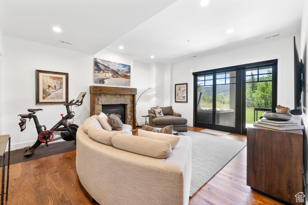 Living room featuring recessed lighting, wood finished floors, and a stone fireplace