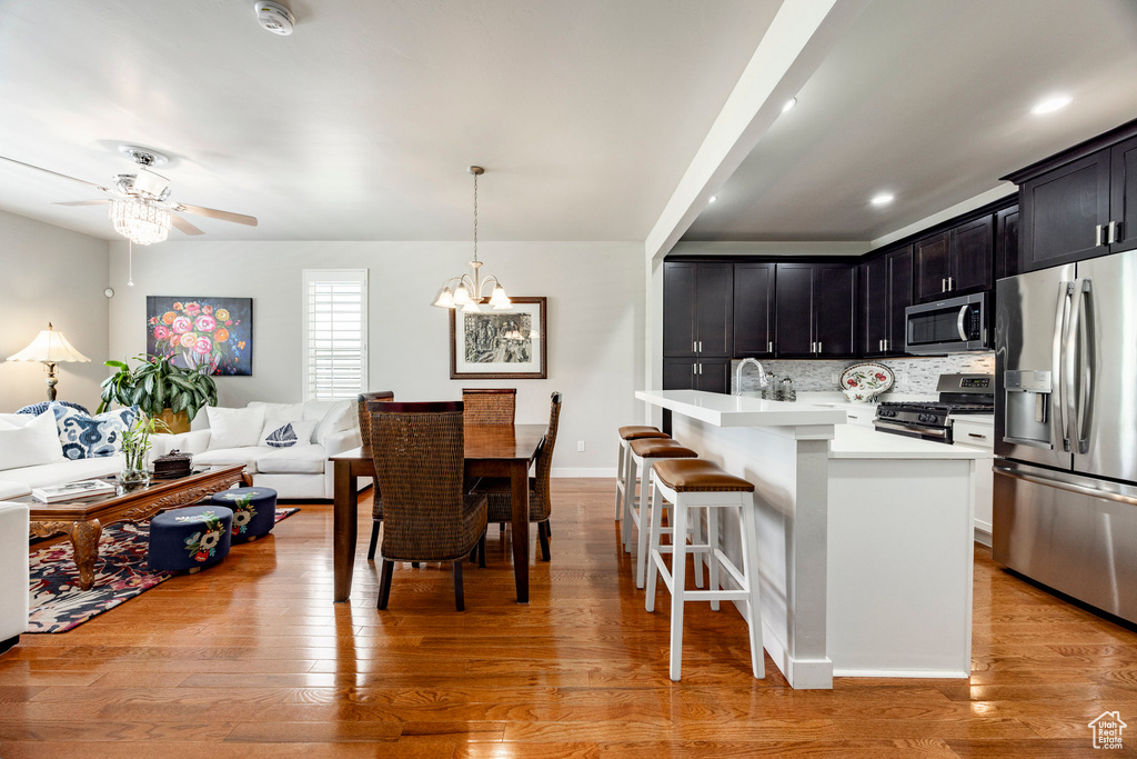 Kitchen with appliances with stainless steel finishes, light countertops, open floor plan, a kitchen breakfast bar, and ceiling fan