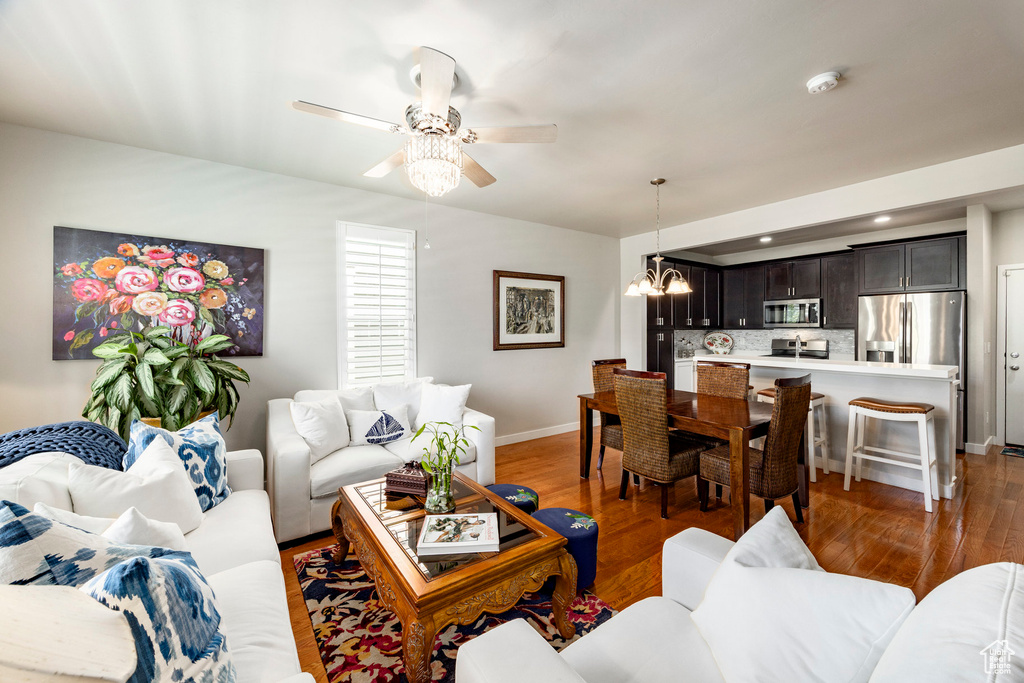 Living room featuring a chandelier, light wood finished floors, a ceiling fan, and recessed lighting