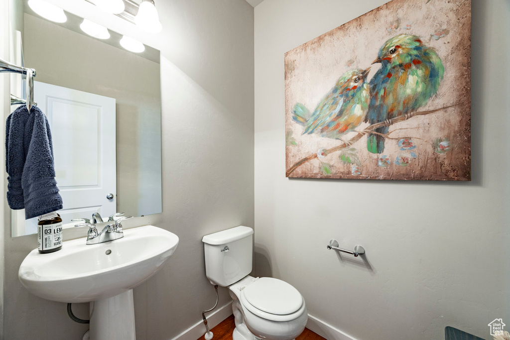 Half bath with toilet and wood finished floors