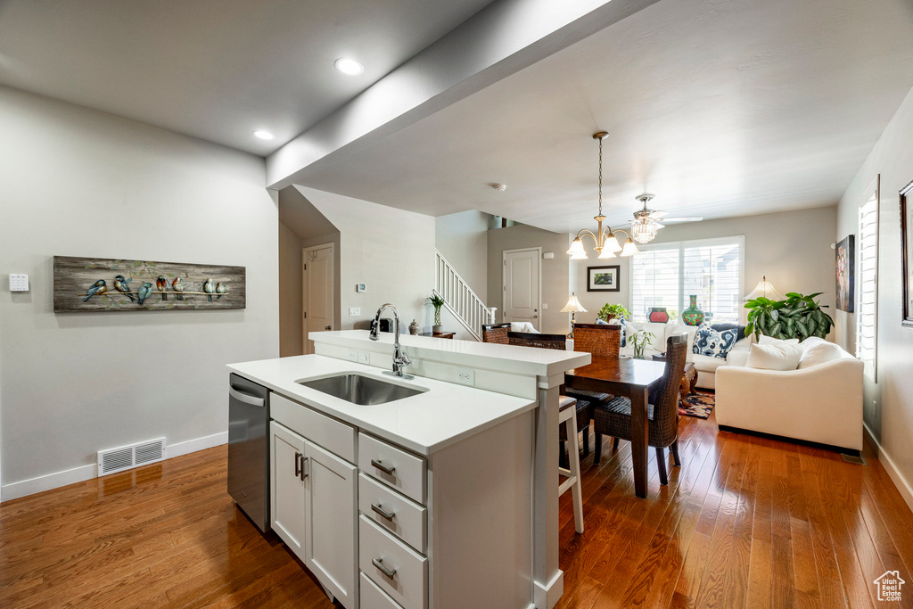 Kitchen featuring open floor plan, an island with sink, dark wood-style flooring, a chandelier, and a kitchen bar