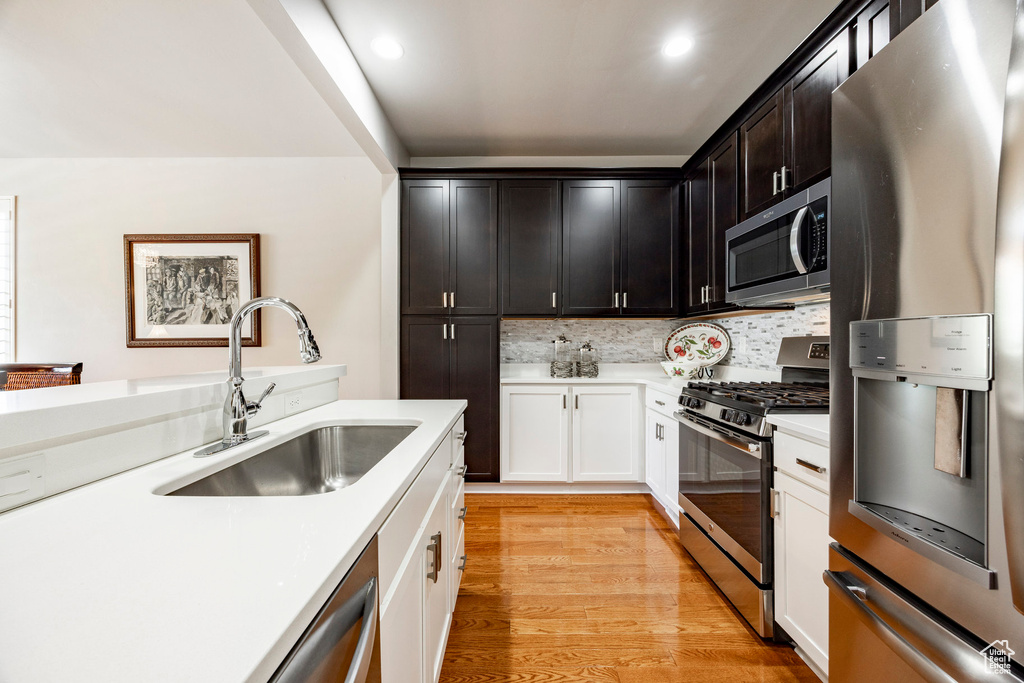 Kitchen with appliances with stainless steel finishes, light countertops, decorative backsplash, light wood-type flooring, and recessed lighting