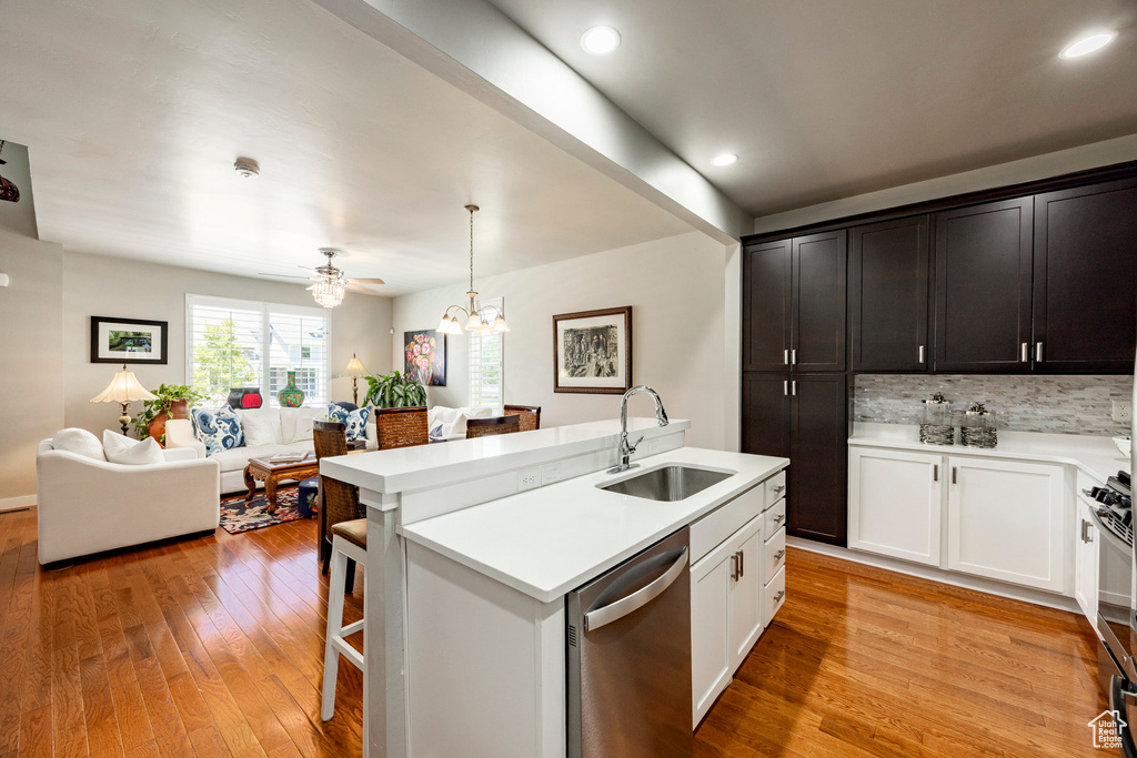 Kitchen with open floor plan, stainless steel appliances, light countertops, light wood finished floors, and tasteful backsplash