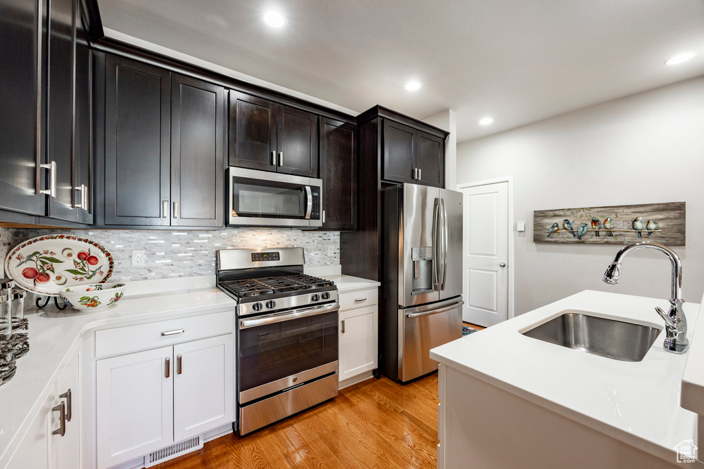 Kitchen featuring appliances with stainless steel finishes, light countertops, backsplash, recessed lighting, and light wood-style floors