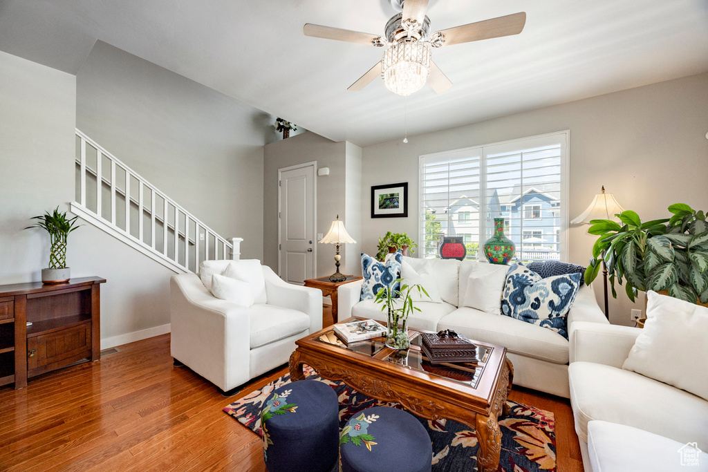 Living room with wood finished floors, ceiling fan, and stairway