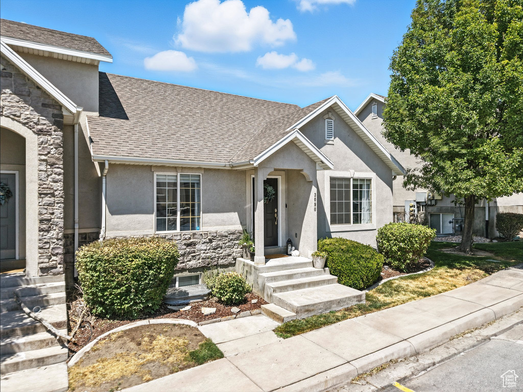 View of front facade featuring stone siding, stucco siding, and roof with shingles