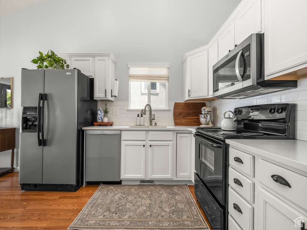 Kitchen featuring stainless steel appliances, white cabinets, and light countertops