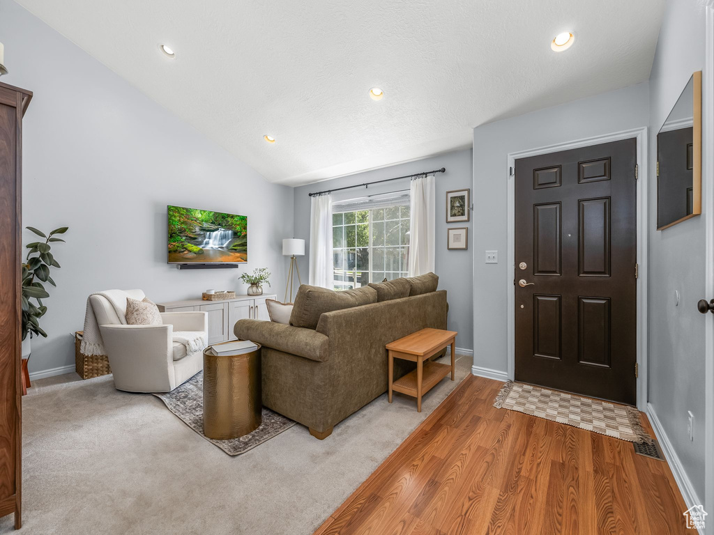 Living area featuring light wood-style flooring, recessed lighting, and lofted ceiling