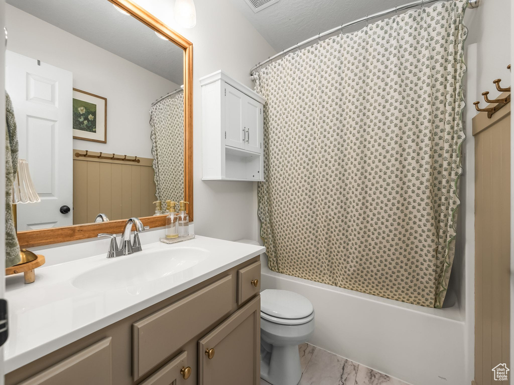 Full bathroom with vanity, shower / bath combo with shower curtain, and marble look tile flooring