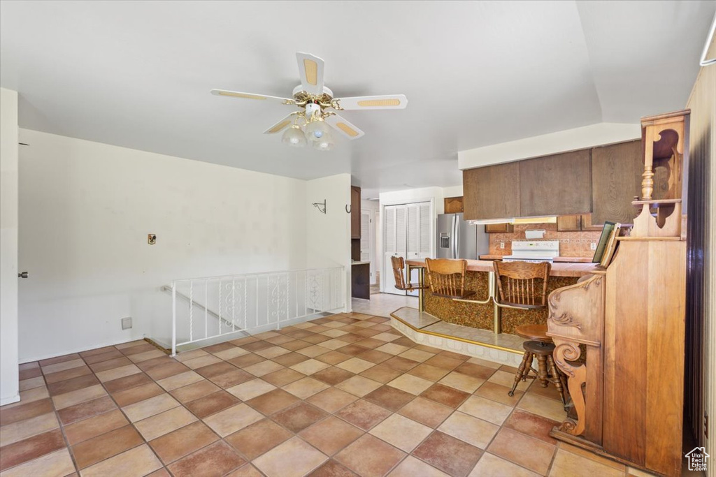 Kitchen featuring a ceiling fan, stainless steel refrigerator with ice dispenser, range, and decorative backsplash