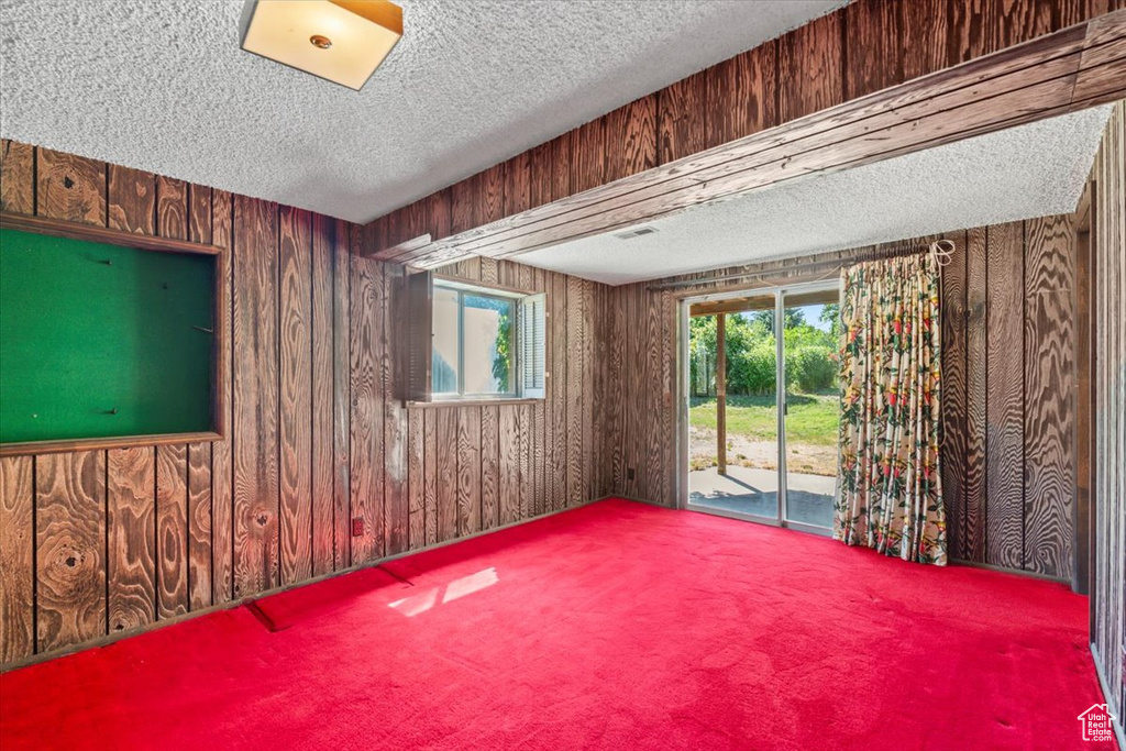 Carpeted spare room with a textured ceiling and wood walls