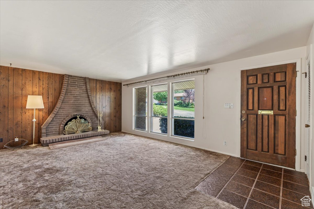 Unfurnished living room with wood walls and dark colored carpet