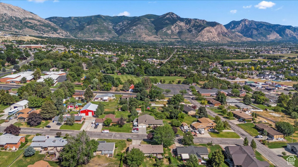 Aerial view of property and surrounding area featuring a mountainous background and nearby suburban area