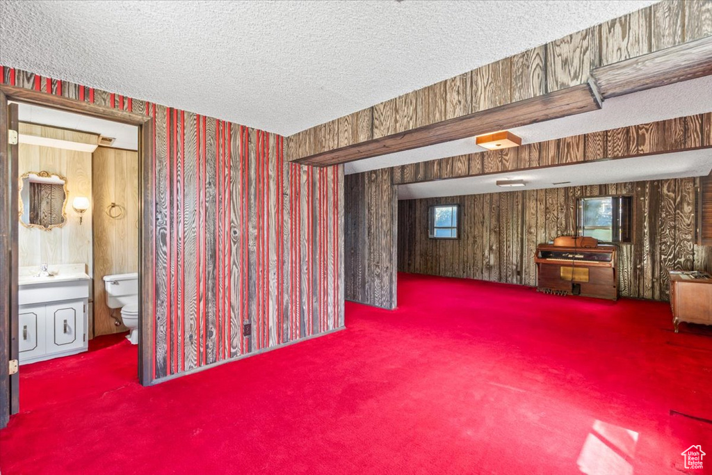 Basement featuring wallpapered walls, carpet, and a textured ceiling