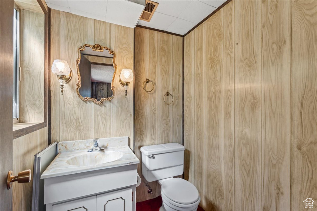 Half bathroom featuring vanity and wooden walls