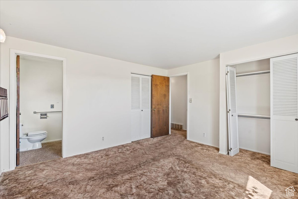 Unfurnished bedroom featuring multiple closets, carpet floors, and connected bathroom