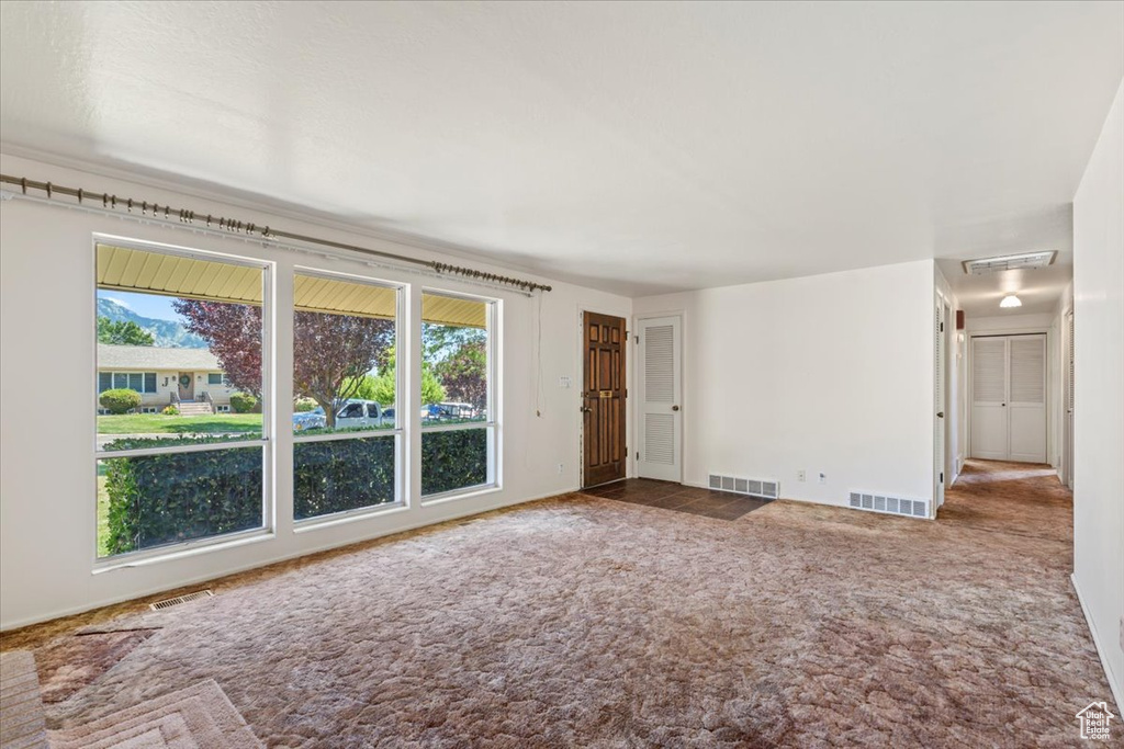 Unfurnished living room featuring plenty of natural light and carpet floors