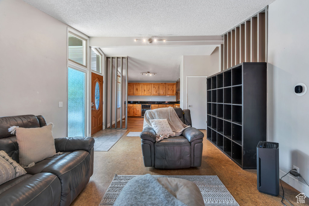 Living room with light carpet, a textured ceiling, and beverage cooler