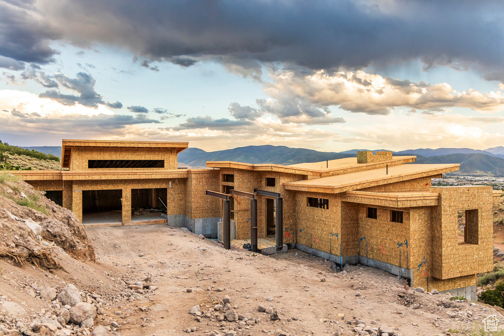 Unfinished property with a mountain view, a chimney, and a garage