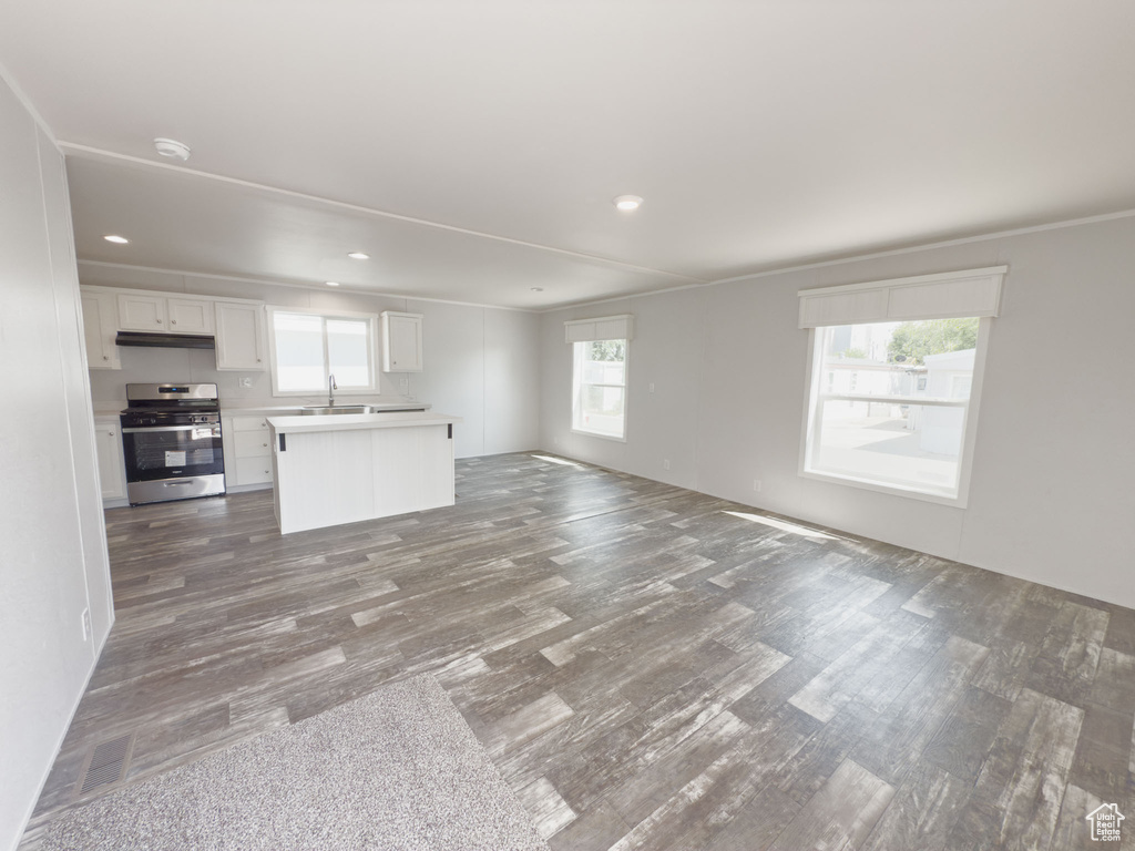 Unfurnished living room featuring dark wood-style floors, healthy amount of natural light, and recessed lighting