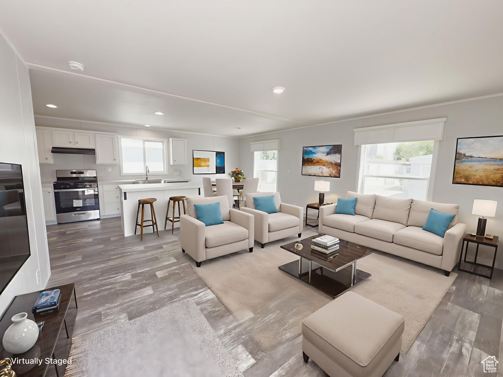 Living room featuring plenty of natural light, recessed lighting, light wood-type flooring, and crown molding