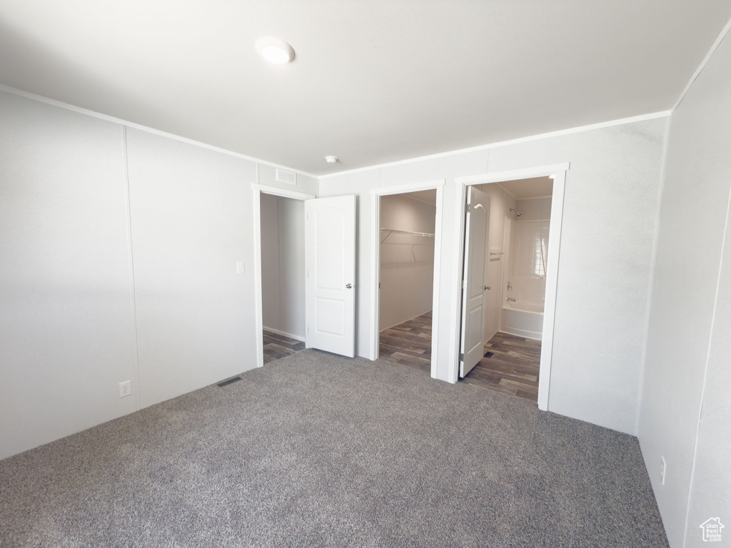 Unfurnished bedroom with carpet, a walk in closet, and connected bathroom