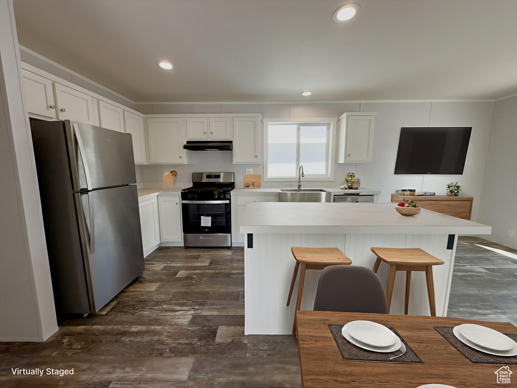 Kitchen with stainless steel appliances, white cabinetry, a kitchen island, a kitchen bar, and light countertops
