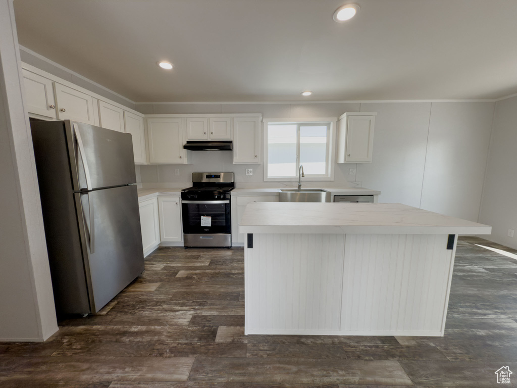 Kitchen featuring stainless steel appliances, white cabinets, light countertops, a center island, and under cabinet range hood