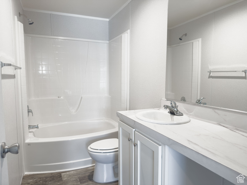Bathroom with wood finished floors, vanity, shower / bath combination, and ornamental molding