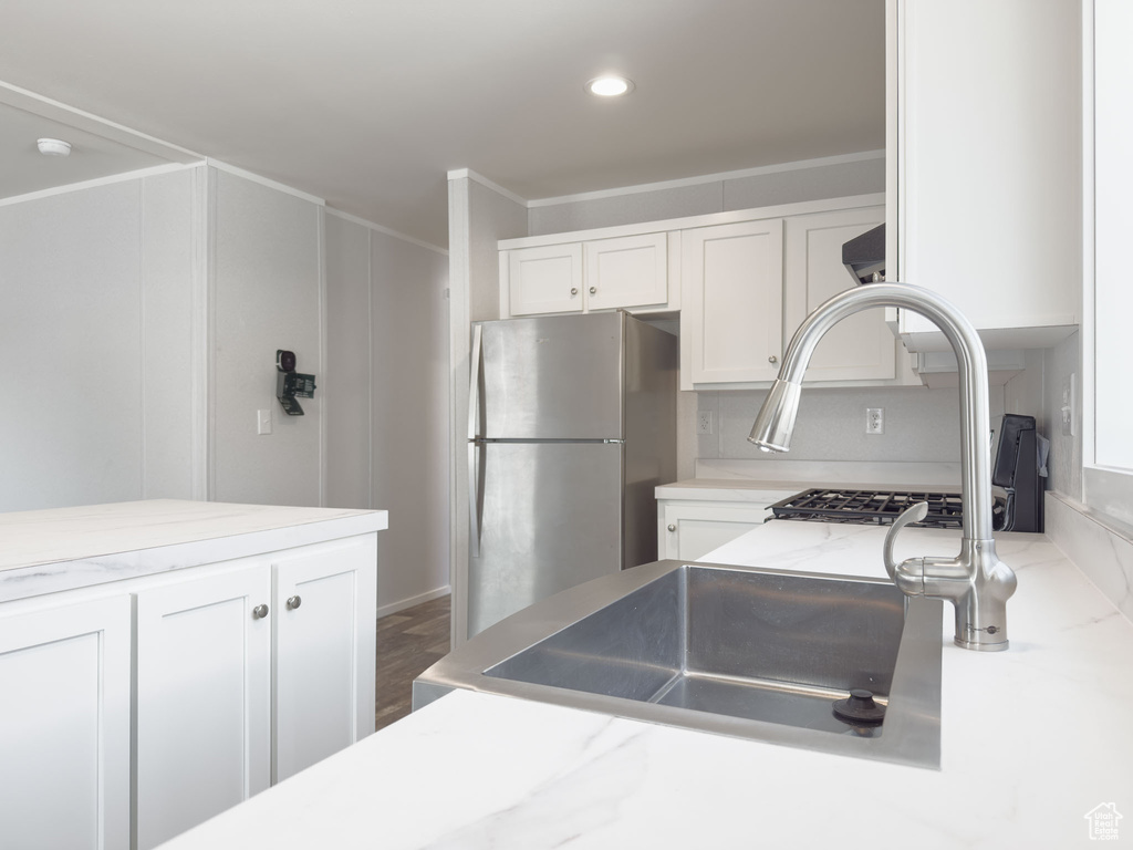 Kitchen featuring freestanding refrigerator, white cabinetry, recessed lighting, crown molding, and light stone counters