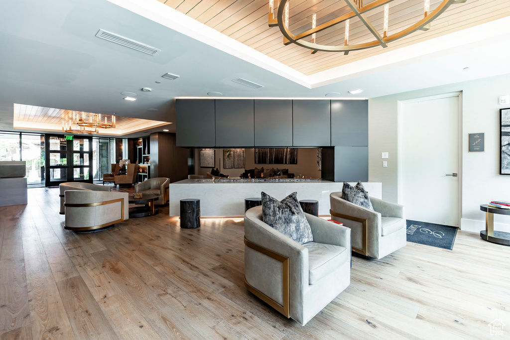 Living area with a chandelier, a raised ceiling, light wood-style floors, and wooden ceiling