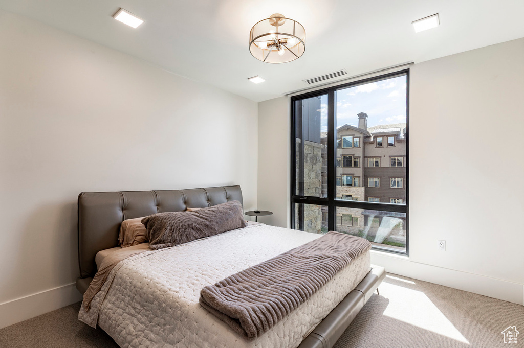 Carpeted bedroom featuring floor to ceiling windows and a chandelier