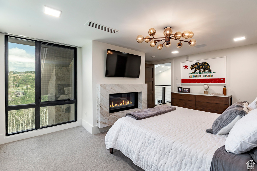 Carpeted bedroom with a high end fireplace and a chandelier